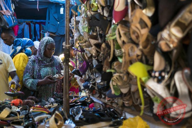 A customer examines a pair of shoes at the Sandaga market in the Plateau district of Dakar, Senegal, on Friday, July 28, 2017. Senegalese voters will elect a new parliament on Sunday in a vote that was marred by violence during campaigning as the ruling coalition is challenged by a 91-year-old former president and the imprisoned mayor of the capital, Dakar. Photographer: Xaume Olleros/Bloomberg via Getty Images